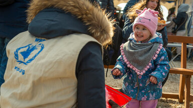WFP staff from the back talks to a smiling kid at a distribution point