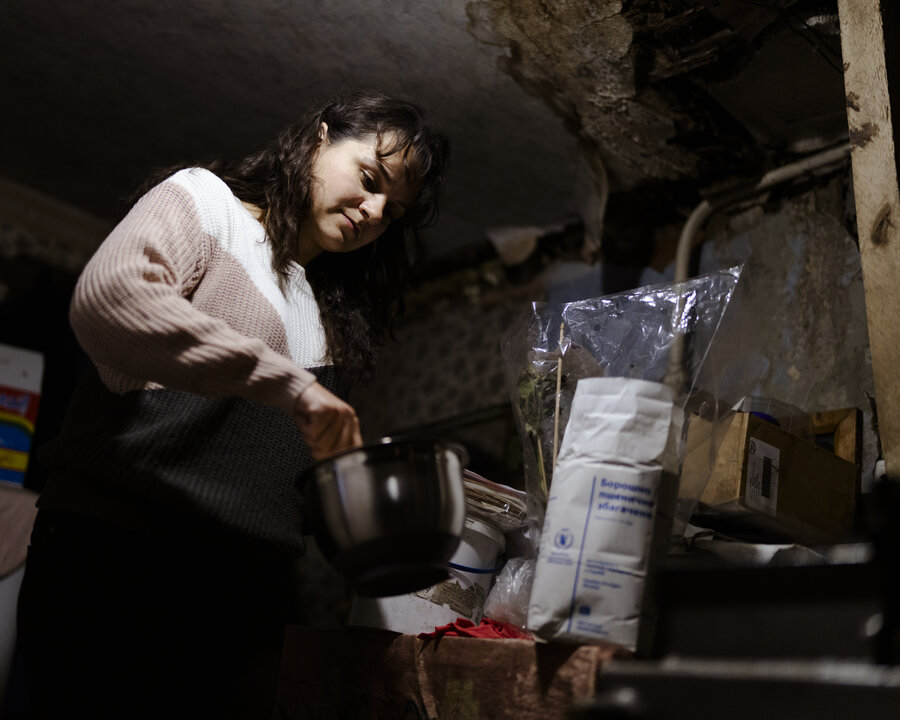 People carry WFP food boxes outside a warehouse, transporting aid supplies as part of a distribution effort in a cold weather setting.